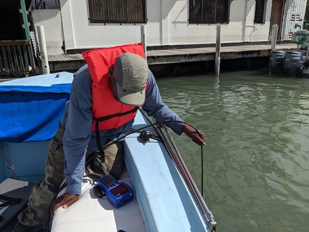 Photo of a technician taking water quality measurements over the side of a boat