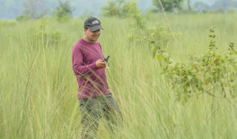 A man standing in a field in Nepal doing research
