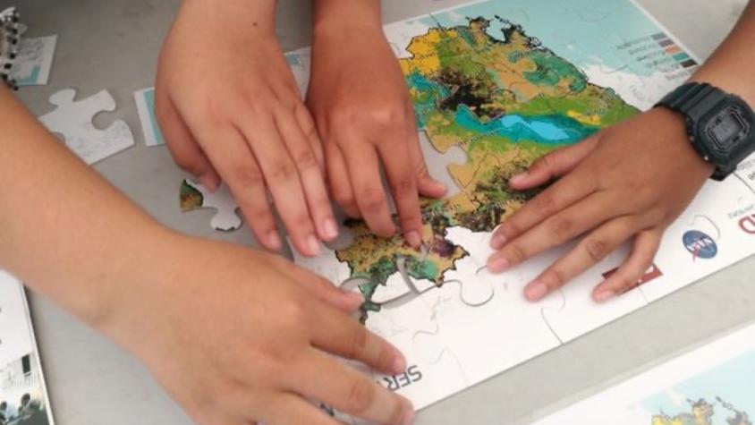 hands putting together a puzzle of southeast asia with logos of SERVIR and NASA